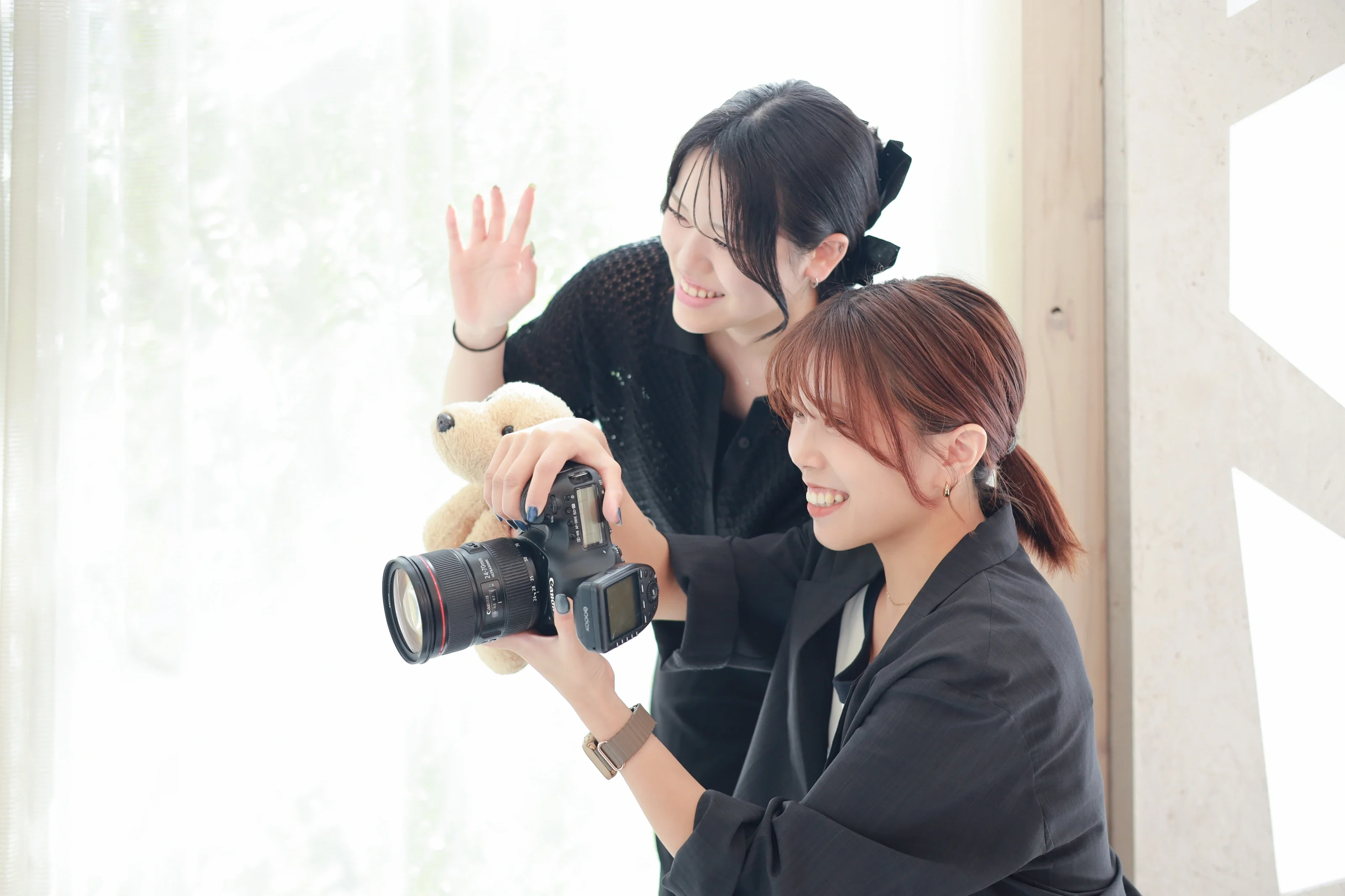 ぬいぐるみを手に笑うフォトグラファーアシスタントとカメラを構えるフォトグラファー